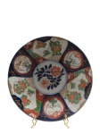 IMARI, (Japão, séc. XVII), Prato decorativo confeccionado em porcelana japonesa esmaltada na tonalidade branca, com pintura de flores e folhagens em policromia, verso com decoração floral, apresentando sinais de restauro, medindo 31cm.