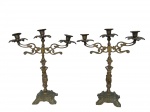 BRONZE, Par de candelabros para 3 velas confeccionadas em bronze, haste vazadas, corpo representando figura feminina, base com cinzel apoiada sobre 4 pés, bobeches no feitio de flor, medindo 35,5x31cm. 1 com mossa nas bobeches.