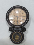 ANSONIA CLOCK CO, Relógio de parede, dito oito, com caixa confeccionada em madeira com placagem escura, mostrador em papel com algarismos romanos e dois furos para dar corda (sinaliza a cada meia hora e hora cheia), parte frontal com portas articuladas e visor superior e inferior envidraçados, acompanha pêndulo, falta chave, funcionando, porém, sem garantia de funcionamento, medindo 53x32x11cm.