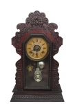 RELÓGIO, Relógio de parede, mostrador cartonado com algarismos arábicos e dois furos para dar corda (sinaliza a cada meia hora e hora cheia), manufatura ANSONIA CLOCK COMPANY (fundada em Connecticut no ano de 1851, por Anson Green Phelps e mais dois relojoeiros Theodore Terry e Franklin C. Andrews, como subsidiária de sua empresa Ansônia Brass, fundada anteriormente em 1844 para fornecer laminados em latão para confecção de relógios, em 1877 adquiriram uma fábrica em New York e transferiram a maior parte de sua produção; em 1878 Thomas Edison visitou a fábrica para experimentar a combinação de relógios com o seu fonógrafo; em 1879 uma segunda fábrica foi aberta no Brooklyn; em 1880 a fábrica de New York incendiou; em 1881 foi reaberta após ter sido reconstruída no mesmo lugar; em 1883 fechou a fábrica de Connecticut; em 1929 foi vendida para Amtorg, que pertencia ao governo Soviético; em 1969 os direitos do uso do nome foram transferidos para Ansônia Clock Company, Lynnwood, Washington), gabinete confeccionado em madeira com entalhes vegetalistas, em alto e baixo relevo, laterais recortadas, apoiada sobre base retangular escalonada, possui pêndulo e chave, mostrador com marcas do tempo, funcionando, porém sem garantias futuras, medindo 58x36x13cm.