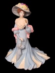 COALPORT (Inglaterra, 1750), "HIGH SOCIETY", Lady Sara, Design Jack Glynn. Escultura confeccionada em porcelana inglesa esmaltada na tonalidade branca representando Lady Sara, uma figura da alta sociedade, vestes esmaltadas na tonalidade azul, peça de edição limitada de 5000 peças, essa é o nº 778, medindo 22,5cm de altura.