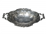 METAL PRATEADO, Fruteira oval confeccionada em metal espessurado a prata, ricamente cinzelado por concheados, volutas, flores e folhagens, alças vazadas, apoiada sobre 4 pés curvos, banho em bom estado, medindo 8,5x38x25cm.