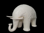 ESCULTURAS, Escultura confeccionada em faiança vitrificada na tonalidade branca representando elefante, elementos geométricos em relevo, duas presas coladas, medindo 20x26x12cm.