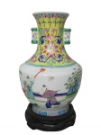 PORCELANA ORIENTAL, Vaso ânfora confeccionada em porcelana oriental esmaltada na tonalidade branca, ricamente decorado por flores e folhagens, cena com figuras e gregas em policromia, apoiada sobre peanha em madeira com entalhes vazados, medindo 26x16x9cm sem a peanha.