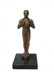 ESCULTURAS, Reprodução do troféu OSCAR confeccionada em bronze, apoiada sobre base quadrangular em mármore escuro. A estatueta foi criada em 1928 por Cedric Gibbons, um designer de produção da MGM, e foi apelidada de Oscar por Margaret Herrick, secretária da AMPAS, que achou que a estatueta parecia com seu tio Oscar. A estatueta do Oscar é feita de metal dourado e tem a forma de um homem alado segurando uma espada. Vestígios de placa na base, medindo 23cm de altura.