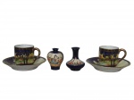 PORCELANA NORITAKE JAPAN, lote composto por quatro peças em, sendo a) Par de xícaras para café com seus respectivos pires em porcelana decoradas com cena campestre em policromia adornada por faixas na tonalidade azul cobalto com detalhes em douração, medindo 4 x 4 cm, da manufatura NORITAKE. b) Dois vasinhos em miniatura confeccionados em faiança decorados com folhagens pintadas à mão. Um dos vasos possui bicados na borda superior. Medidas do maior 4,5 x 4 cm.