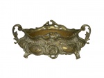 BRONZE, Floreira de mesa confeccionado em bronze, ricamente cinzelado por flores, folhagens, concheados e volutas, alças em arabescos, apoiado sobre 4 pés curvos, acompanha recipiente interno, medindo 12x31x16cm.