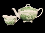 JOHNSON BROTHERS (Staffordshire, Reino Unido, 1883  China, 2015), OLD BRITAIN CASTLES. Bule para chá e cremeira confeccionadas em faiança inglesa esmaltada na tonalidade branca, centro do bule retratando Castelo de Brougham (localiza-se a cerca de 2 milhas a sudeste da cidade de Penrith, na Cumbria, na Inglaterra) e da cremeira retratando Castelo de Ludlow (localiza-se na região de Ludlow, no condado de Shropshire, no Oeste da Inglaterra) e borda com elementos florais e vegetalistas na tonalidade verde, bule craquelado, medindo 13x22,5x13cm e cremeira 6,5x11,5x7cm.