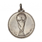 Raríssima medalha de PRATA 925, concedida por ocasião da "XI Copa Mundial de la FIFA - Argentina - 1978". Peça oficial da Copa do Mundo de Futebol, licenciada pela FIFA. Traz a imagem da Taça e a inscrição: "Fifa World Cup". Mede 3,4 cm de diâmetro.