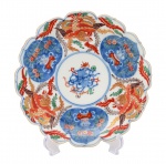 Arte Oriental - Belíssimo prato de porcelana japonesa dita "Imari", profusamente decorados, em sua policromia característica, pelos esmaltes nas cores azul índigo, vermelho e "rouge de fer" sobre fundo branco, reproduzindo as temáticas floral, ave do paraíso e grafismos. Presença de "double ring" e assinatura no verso. Japão -Séc. XIX/ XX. Med. 22 cm (ME). Marcas do tempo. Coleção Particular Rio de Janeiro/RJ.   Nota: PORCELANA JAPONESA - IMARI. Das muitas escolas consagradas de cerâmicas e porcelanas japonesas, possivelmente a Imari é das mais conhecidas no exterior por estar sendo exportada desde o final do século XVII, ainda quando o relacionamento internacional do Japão era efetuado exclusivamente pelos holandeses, que passou por uma abertura na Era Meiji. O acervo mais importante de peças Imari encontra-se atualmente no Museu de Cerâmica Oriental de Osaka. Como é sabido, os japoneses aperfeiçoaram as técnicas aprendidas dos chineses, por intermédio dos artistas coreanos, tendo se concentrado inicialmente na região sul do Japão, mais próxima da península coreana. Sua exportação substituiu a chinesa, sendo efetuada pelo porto Imari, ficando consagrada por este nome. Os chineses já produziam porcelanas quando a Europa ainda contava somente com cerâmicas de baixa temperatura, como estão apresentadas no Museu de Servrés, na França. As peças chinesas ficaram difíceis de serem exportadas para a Europa diante dos distúrbios políticos na passagem da dinastia Ming para a Qing, na década de 1640. A Companhia das Índias Orientais holandesa tinham um entreposto em Nagasaki e a exportação do Japão começou em 1659. Estas peças de porcelana eram adequadas para os palácios e residências da aristocracia europeia. As grandes peças Imari eram utilizadas como ornamentos e aparentam pouco uso. Mas existem variadas peças, como pratos e outros utensílios, todos com desenhos característicos, sendo identificados também pelos esmaltes utilizados. É comum encontrar ainda hoje peças de séculos nos antiquários de todo o mundo, que atualmente alcanças preços elevados. A utilização do ouro, que já atraía os europeus desde a época de Marco Polo, mas que surpreendem os bons apreciadores de cerâmicas e porcelanas, sendo que existem escolas que mantiveram seus estilos, principalmente na região de Arita, entre os quais um bastante conhecido é o chamado Kakiemon. Tudo indica que muitas destas peças eram encomendadas pelos europeus, onde algumas cores que eram obtidas pelos produtores japoneses também se destacavam, permitindo o desenvolvimento do chamado Japonismo no século XIX. Nesta época, a admiração era recíproca e também os japoneses se interessavam pelas obras de arte, notadamente dos artistas europeus, com destaque dos franceses. Fonte: https://criart.com.br/wp-content/uploads/2021/03/Material-Extra-Porcelana-Japonesa.pdf