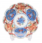 Arte Oriental - Belíssimo prato de porcelana japonesa dita "Imari", profusamente decorados, em sua policromia característica, pelos esmaltes nas cores azul índigo, vermelho e "rouge de fer" sobre fundo branco, reproduzindo as temáticas floral, ave do paraíso e grafismos. Presença de "double ring" e assinatura no verso. Japão -Séc. XIX/ XX. Med. 22 cm (ME). Marcas do tempo. Coleção Particular Rio de Janeiro/RJ.   Nota: PORCELANA JAPONESA - IMARI. Das muitas escolas consagradas de cerâmicas e porcelanas japonesas, possivelmente a Imari é das mais conhecidas no exterior por estar sendo exportada desde o final do século XVII, ainda quando o relacionamento internacional do Japão era efetuado exclusivamente pelos holandeses, que passou por uma abertura na Era Meiji. O acervo mais importante de peças Imari encontra-se atualmente no Museu de Cerâmica Oriental de Osaka. Como é sabido, os japoneses aperfeiçoaram as técnicas aprendidas dos chineses, por intermédio dos artistas coreanos, tendo se concentrado inicialmente na região sul do Japão, mais próxima da península coreana. Sua exportação substituiu a chinesa, sendo efetuada pelo porto Imari, ficando consagrada por este nome. Os chineses já produziam porcelanas quando a Europa ainda contava somente com cerâmicas de baixa temperatura, como estão apresentadas no Museu de Servrés, na França. As peças chinesas ficaram difíceis de serem exportadas para a Europa diante dos distúrbios políticos na passagem da dinastia Ming para a Qing, na década de 1640. A Companhia das Índias Orientais holandesa tinham um entreposto em Nagasaki e a exportação do Japão começou em 1659. Estas peças de porcelana eram adequadas para os palácios e residências da aristocracia europeia. As grandes peças Imari eram utilizadas como ornamentos e aparentam pouco uso. Mas existem variadas peças, como pratos e outros utensílios, todos com desenhos característicos, sendo identificados também pelos esmaltes utilizados. É comum encontrar ainda hoje peças de séculos nos antiquários de todo o mundo, que atualmente alcanças preços elevados. A utilização do ouro, que já atraía os europeus desde a época de Marco Polo, mas que surpreendem os bons apreciadores de cerâmicas e porcelanas, sendo que existem escolas que mantiveram seus estilos, principalmente na região de Arita, entre os quais um bastante conhecido é o chamado Kakiemon. Tudo indica que muitas destas peças eram encomendadas pelos europeus, onde algumas cores que eram obtidas pelos produtores japoneses também se destacavam, permitindo o desenvolvimento do chamado Japonismo no século XIX. Nesta época, a admiração era recíproca e também os japoneses se interessavam pelas obras de arte, notadamente dos artistas europeus, com destaque dos franceses. Fonte: https://criart.com.br/wp-content/uploads/2021/03/Material-Extra-Porcelana-Japonesa.pdf