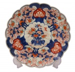 Arte Oriental - Belíssimo prato de porcelana japonesa  dita "Imari", profusamente decorados, em sua policromia característica, pelos esmaltes nas cores azul índigo, vermelho e "rouge de fer" sobre fundo branco, reproduzindo as temáticas floral e vegetalista. Presença de "double ring". Japão -Séc. XIX/XX.  Med. 22 cm (ME). Marcas do tempo. Acervo Particular Rio de Janeiro/RJ. Nota: PORCELANA JAPONESA - IMARI. Das muitas escolas consagradas de cerâmicas e porcelanas japonesas, possivelmente a Imari é das mais conhecidas no exterior por estar sendo exportada desde o final do século XVII, ainda quando o relacionamento internacional do Japão era efetuado exclusivamente pelos holandeses, que passou por uma abertura na Era Meiji. O acervo mais importante de peças Imari encontra-se atualmente no Museu de Cerâmica Oriental de Osaka. Como é sabido, os japoneses aperfeiçoaram as técnicas aprendidas dos chineses, por intermédio dos artistas coreanos, tendo se concentrado inicialmente na região sul do Japão, mais próxima da península coreana. Sua exportação substituiu a chinesa, sendo efetuada pelo porto Imari, ficando consagrada por este nome. Os chineses já produziam porcelanas quando a Europa ainda contava somente com cerâmicas de baixa temperatura, como estão apresentadas no Museu de Servrés, na França. As peças chinesas ficaram difíceis de serem exportadas para a Europa diante dos distúrbios políticos na passagem da dinastia Ming para a Qing, na década de 1640. A Companhia das Índias Orientais holandesa tinham um entreposto em Nagasaki e a exportação do Japão começou em 1659. Estas peças de porcelana eram adequadas para os palácios e residências da aristocracia europeia. As grandes peças Imari eram utilizadas como ornamentos e aparentam pouco uso. Mas existem variadas peças, como pratos e outros utensílios, todos com desenhos característicos, sendo identificados também pelos esmaltes utilizados. É comum encontrar ainda hoje peças de séculos nos antiquários de todo o mundo, que atualmente alcanças preços elevados. A utilização do ouro, que já atraía os europeus desde a época de Marco Polo, mas que surpreendem os bons apreciadores de cerâmicas e porcelanas, sendo que existem escolas que mantiveram seus estilos, principalmente na região de Arita, entre os quais um bastante conhecido é o chamado Kakiemon. Tudo indica que muitas destas peças eram encomendadas pelos europeus, onde algumas cores que eram obtidas pelos produtores japoneses também se destacavam, permitindo o desenvolvimento do chamado Japonismo no século XIX. Nesta época, a admiração era recíproca e também os japoneses se interessavam pelas obras de arte, notadamente dos artistas europeus, com destaque dos franceses. Fonte: https://criart.com.br/wp-content/uploads/2021/03/Material-Extra-Porcelana-Japonesa.pdf