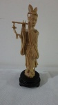 Estatueta em marfinite, representando figura de mulher tocando instrumento. Mede 18 cm de altura