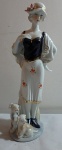 Linda estatueta em porcelana chinesa em perfeito estado, dama ricamente policromada acompanhada de dois cachorrinho de estimação e chapéu decorado com flores, vestido filetado a ouro. Alt. 29cm.