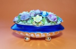 Belíssimo porta joias em porcelana vitrificada, apresenta formato oval, tampa encimada por flores diversas e policromadas decoradas com realces dourados, apoiada sobre pés em bola. Marca PALB - Medida: 22,5 X 13 X 13 cm - Vide fotos!