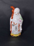 PORCELANA CHINESA, uma (1) escultura policromada, pintada a mão, detalhes a ouro, representando o Deus FUKUROKUJU, segundo o Xintoísmo, Mitologia e Folclore Japonês, Deus da longevidade e sabedoria, representado por uma longa barba branca trazendo na mão um cetro ou bastão (saku) sagrado onde esta pendurado um pergaminho (makimono) contendo as escritas da sabedoria mundial, considerado Deus da ecologia, as vezes acompanhado por um veado, tartaruga ou uma garça tipo grou (tsuru), outras vezes de um pêssego, ter sua estatueta traz popularidade e garante longevidade, integrante do Shichi Fukujin (os 7 Deuses da Boa Sorte, Fortuna e Felicidade), marca de origem na base em legenda e caracteres, medindo 14 cm altura.