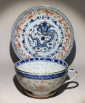 PORCELANA ORIENTAL - Padrão Imari. Xícara para coleção padrão Imari, profusamente decorada com motivos florais no bojo, tendo imponente figura de dragão na parte interna ricamente decorada. Peça acompanhada por pires no mesmo padrão. Presença de técnica de transparência em pontos coordenados que remetem a grão de arroz em ambas as peças. Medidas da xícara: 09 de diâmetro X 5,5 de altura. Sem detalhes.