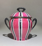 PORCELANA FRANCESA - Limoges C. S. A. Pequeno Potiche em Porcelana esmaltada, na cor magenta. Detalhes de listras, pega da tampa e alças laterais em preto. Sinal de cola na pega da tampa. Medidas: 8 cm de altura.