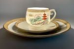 PORCELANA ORIENTAL - Sacura / made in Japan. Xícara acompanhada de pires e prato para pães ou biscoitos. Decoração a ouro, com garças, pagode paisagem lacustre. Presença de figura de gueixa no fundo da xícara em técnica de litofania.