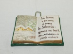 Placa decorativa na forma de livro, descrevendo idades da mulher em italiano, em cerâmica. Medindo 14cm x 10cm. Leve bicado.