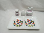 Lote de petisqueira, galheta, saleiro e pimenteiro, em porcelana. Medindo 24,5cm x 14cm x 3,5cm de altura.