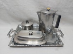 Lote de bandeja em metal prateado, bule, açucareiro e manteigueira em aço inox. Medindo a bandeja 30,5cm x 22,5cm x 37cm alça alça.