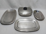 Baixela com 4 peças em aço inox, composto de legumeira, 2 travessas retangulares rasa e 1 travessa retangular funda. Medindo a legumeira 23,5cm x 23,5cm x 5,5cm de altura.