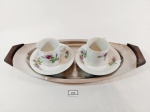 conjunto de serviço de café, composto por duas xícaras em porcelana branca com decoração floral e bandeja oval em metal marcado Gazola, com borda em madeira. Med: 5,5 x 10 cm; 15,5 x 35 cm.