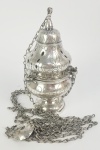 MAGNIFICO TURÍBULO EM PRATA DE LEI  COM LINDA DECORAÇÃO EM GUILLOCHES VEGETALISTAS.DE BELISSIMA CONSTRUÇÃO E ESTRUTURA ROBUSTA BRASIL, MEADOS DO SEC. XIX. 24 CM DE ALTURA (TURIBULO SEM CONSIDERAR O TAMANHO DAS CORRENTES). 740 GNOTA: O uso do incenso é antiquíssimo, anterior à própria vinda de Cristo. As primeiras menções ao seu uso provavelmente vem dos egípcios, no III milênio A.C. Seu uso sempre foi relacionado à aromatização e purificação do ambiente e a uma oferta de odor agradável à divindade. Os hebreus, por exemplo, utilizavam amplamente o incenso no Templo de Jerusalém, onde havia o altar do Incenso, no qual era queimado continuamente o incenso em tributo a Deus. (Cf. Ex 30; Lv 16,12). Talvez por ser amplamente utilizado entre os pagãos, a Igreja nos seus primeiros anos evitava o seu uso dentro da Liturgia, para fazer uma distinção clara entre a liturgia pagã e a liturgia cristã, em particular porque o incenso oferecido aos deuses pagãos era uma grande traição à fé, e vários santos foram torturados e martirizados por se recusarem a fazê-lo. (Como S. Cassiano, S. Policarpo, S. Dinis, S. Cristina, S. Jorge e muitos outros). Vemos, no entanto, o incenso sendo usado como sinal de honra e oração por um defunto, como podemos ver no Testamento de Santo Efrén,no ano373. Uma vez que foi destruído o paganismo, a partir do século IV o incenso começou a ganhar um espaço maior na Liturgia, sobretudo nas dedicações do altar. A primeira igreja a receber o incenso foi a igreja do Santo Sepulcro, e então o uso foi se espalhando.A primeira aparição formal do incenso em Roma é do século VII, como gesto de honra ao papa e ao Evangeliário. Dentro da Missa, o incenso começou a ser utilizado por volta do século IX, no início da Missa, de modo similar como é hoje:Altar, clero, oblatas.Isto se fazia se passando o incensário (Uma espécie de vaso onde se queimava o incenso) à frente dos objetos e das pessoas. Isso foi se desenvolvendo até chegar ao modo como temos hoje. A naveta também foi ganhando sua forma de navio a partir desta época. Vemos o incenso nas Sagradas Escrituras aparecerem várias vezes. Além dos já conhecidos significados de aromatização e de purificação contra os demônios, sendo o incenso um sacramental, destacam-se os significados:Adoração,Honra e Oração. Talvez o significado mais bonito tenha sido inspirado no livro do Apocalipse: E veio outro anjo, e pôs-se junto ao altar, tendo um incensário de ouro; e foi-lhe dado muito incenso, para o pôr com as orações de todos os santos sobre o altar de ouro, que está diante do trono. E a fumaça do incenso subiu com as orações dos santos desde a mão do anjo até diante de Deus. Assim a fumaça do turibulo que sobe aos céus representa as orações que sobem a Deus. (https://manualdocoroinha.com.br/objetos-liturgicos/turibulo