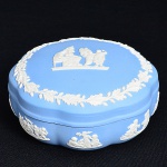 Wedgwood - Caixa com tampa em porcelana Inglesa, marcada, nas cores azul e branca, figuras em alto relevo, medindo 6 cm por 13 cm de diâmetro.