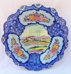 ALCOBAÇA - Grandioso medalhão em faiança portuguesa com decoração de cena campestre e flores com detalhes vazados e borda recortada. Diâmetro: 36 cm.