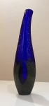 Vaso artístico em vidro soprado da Kosta Boda, assinado pela renomada artista Monica Backström. Peça de edição limitada, representativa do expressivo design escandinavo contemporâneo.Confeccionado em vidro artístico de alta qualidade, apresenta forma alongada e levemente assimétrica, com elegante movimento ascendente e boca inclinada. A coloração em azul cobalto intenso na parte superior contrasta com a base em tonalidade escura texturizada, criando efeito visual sofisticado e grande profundidade cromática. A superfície superior lisa e brilhante dialoga com o acabamento granulado da base, característica marcante do trabalho da artista. Mede aproximadamente 37 cm de altura.Peça escultórica de forte presença decorativa, ideal para colecionadores de vidro artístico nórdico, apreciadores do design moderno e composições de destaque em ambientes sofisticados.
