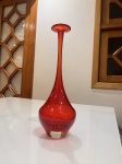 Vaso artístico em vidro soprado, possivelmente Murano, representativo do refinado design italiano.Apresenta forma elegante e escultural, com corpo bojudo que se eleva em longo e esguio gargalo, culminando em boca ampla e delicadamente aberta. A coloração vermelho rubi intenso, translúcida e luminosa, confere grande impacto visual, enquanto a base em cristal claro levemente ambarado cria contraste sofisticado e valoriza a profundidade da cor.O acabamento é liso e brilhante, evidenciando a qualidade do sopro e o excelente equilíbrio formal da peça. Seu desenho harmonioso e proporções alongadas conferem leveza e imponência ao mesmo tempo.Mede aproximadamente 31 cm de altura.Peça decorativa de forte presença estética, ideal para compor ambientes elegantes, coleções de vidro artístico ou decoração de destaque.