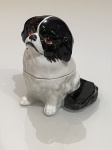 Cachorro em Porcelana com Compartimento Interno  Peça DecorativaCharmosa peça em porcelana representando um cãozinho de expressão marcante e olhar expressivo em tom avermelhado. Ricamente esmaltado, apresenta acabamento brilhante, com pelagem em preto e branco cuidadosamente pintada à mão, valorizando os detalhes do rosto e das orelhas.Além de decorativo, o exemplar possui compartimento interno, funcionando como uma pequena caixa. A parte superior (cabeça) é removível, revelando espaço interno ideal para guardar pequenos objetos, joias ou lembranças.O contraste entre o esmalte branco e o preto intenso confere elegância à peça, enquanto o formato lúdico adiciona personalidade à decoração. Ideal para compor penteadeiras, estantes, aparadores ou integrar coleções de porcelanas figurativas.Sem marca aparente de fabricante.Estado de conservação: bom, compatível com o tempo, sem quebras aparentes.Peça delicada e funcional, que une utilidade e charme decorativo em um único objeto.