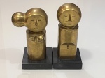 Aldemir MartinsPar de esculturasBronze patinado sobre base.Assinadas.Altura aproximada 25 cm.Par de esculturas em bronze representando figuras estilizadas, com cabeças circulares e feições simplificadas, características da linguagem sintética e expressiva associada à produção de Aldemir Martins. Corpos de volumetria cilíndrica e composição geométrica, apoiados sobre bases retangulares.Assinadas.