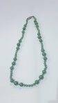 Colar longo em estilo Art Déco, confeccionado com contas de vidro tcheco verde, intercaladas por nós. Fecho de metal. Estado de conservação: muito bom. Peça elegante, representativa do design de joias da época."