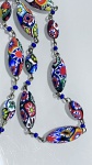 COLAR EM VIDRO MILLEFIORI MULTICOLORIDOColar composto por contas em vidro na técnica millefiori, caracterizadas pela presença de padrões florais e geométricos multicoloridos incorporados à massa vítrea. As contas apresentam formatos predominantemente ovais e alongados, com superfície polida e alto brilho.A composição destaca-se pela riqueza cromática  com tons de azul, vermelho, branco, verde e amarelo  e pela variedade de desenhos, típicos dessa técnica tradicional de origem veneziana.Montagem articulada com elos metálicos interligando as contas, intercaladas por pequenas esferas em vidro azul. Conjunto com bom movimento e caimento.Material: vidro millefiori.Elementos complementares: metal (elos e conexões).Estado de conservação: bom
