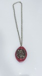 COLAR COM PINGENTE ORNAMENTAL EM RESINA E METALColar composto por corrente metálica em tom dourado, sustentando pingente de grandes dimensões em material sintético (resina/acrílico) na tonalidade rosa.O pingente apresenta formato ovalado e acabamento polido, com aplicação frontal de elemento metálico vazado em tom dourado, de desenho ornamental com inspiração arabesca/filigranada, conferindo destaque e sofisticação à peça.Elemento superior com detalhe em conta esférica em tom rosado, integrando a composição entre corrente e pingente.Material: metal (corrente e aplicação) e resina/acrílico (pingente).Fecho: metálicoEstado de conservação: bom