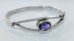 BRACELETE EM PRATA DE LEI COM PEDRA NATURAL EM TONALIDADE VIOLETABracelete em prata de lei, com estrutura rígida e design contemporâneo, apresentando aro liso com elemento central em formato oval.A peça é ornamentada com pedra natural lapidada, em tonalidade violeta, com acabamento facetado que confere brilho e destaque ao conjunto. A pedra encontra-se engastada em aro central, criando composição elegante e equilibrada.Sistema de abertura lateral com fecho articulado, proporcionando praticidade e segurança ao uso.PERÍODO: contemporâneoMATERIAL: prata de lei e pedra naturalTÉCNICA: ourivesaria, lapidação e montagemFECHO: articulado com encaixeESTADO DE CONSERVAÇÃO: bom estado geral, com leves sinais de uso compatíveis, sem danos aparentes na pedra ou na estrutura.OBSERVAÇÕES: peça de estética refinada, destacando-se pela pureza do design e pela beleza da pedra em tonalidade violeta, ideal para uso elegante ou composição de acervo de joias em prata.