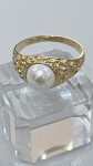 ANEL EM METAL DOURADO COM PÉROLAAnel em metal dourado, de aro delicado com acabamento texturizado, apresentando pérola central em destaque. O design orgânico e levemente irregular confere charme e personalidade à peça, valorizando o brilho suave da pérola.Com estética clássica e atemporal, é uma peça elegante que combina simplicidade e sofisticação.PERÍODO: contemporâneoMATERIAL: metal dourado e pérolaTÉCNICA: fundição e fixação por encaixeESTADO DE CONSERVAÇÃO: bom estado geral