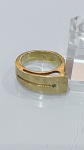 ANEL EM METAL DOURADO COM PEDRA VERDEAnel em metal dourado, de design contemporâneo e linhas minimalistas, apresentando aro largo com recortes vazados que criam efeito moderno e elegante.A peça é finalizada com pequena pedra verde aplicada lateralmente, conferindo delicado ponto de cor e sofisticação ao conjunto.PERÍODO: contemporâneoMATERIAL: metal dourado e pedra verdeTÉCNICA: fundição e aplicação de pedraESTADO DE CONSERVAÇÃO: bom estado geral