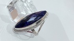 ANEL EM PRATA DE LEI COM PEDRA AZUL FACETADAAnel confeccionado em prata de lei, sem marca de teor aparente, apresentando aro estruturado com design elegante e acabamento trabalhado nas laterais, com detalhes em relevo que enriquecem a composição da peça.Destaque para a pedra central de formato alongado, em lapidação facetada, exibindo coloração azul intensa e profunda, com nuances que transitam entre o azul marinho e reflexos levemente violáceos conforme a incidência de luz. A lapidação proporciona brilho discreto e elegante, evidenciando a profundidade da tonalidade.Montagem elevada, valorizando a pedra e conferindo imponência ao conjunto. Peça de presença marcante, com excelente impacto visual e estética refinada.