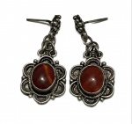 PAR DE BRINCOS EM PRATA DE LEI COM PEDRAS EM TONS ÂMBARPar de brincos confeccionados em prata de lei, sem marca de teor aparente, com estrutura pendente.Apresentam composição central com pedras de formato oval, em tonalidade âmbar, exibindo coloração quente e translúcida, com nuances que variam entre o mel e o castanho-avermelhado conforme a incidência de luz.A moldura é trabalhada em relevo com elementos ornamentais que remetem a forma floral, com detalhes granulares e acabamento levemente oxidado, evidenciando o desenho.Sistema de fixação por gancho. Peças articuladas, proporcionando leve movimento ao uso.Conjunto em bom estado geral de conservação.