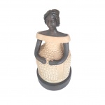 Escultório em argila representando negra com vestido de gala creme apoiado em base circular, fala em um dos dedos e imperceptível   bicado no cabelo, Alt. 25, Diam. 13 cm.