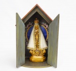 Nossa Senhora de Aparecida - imagem em estuque policromada no tom dourado, manto com aplicações de pérolas sintéticas e pérolas douradas - med. 27x10x6,5 cm, acompanha oratório de viagem em madeira entalhada e patinada, tendo na parte interna do fundo do oratório gravura de Nossa Senhora de Fátima - med. 35,5x22x16 cm