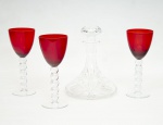 Lote constando de quatro peças sendo uma licoreira - decanters em cristal da Bohemia com lapidação de frisos e bisotados - med. 20x14 cm de diâmetro na base (base com marcas de mofo) e três copos para vinho com bojos em vidro no tom vermelho, hastes e bases translúcidas, hastes na forma de esferas - med. 18,5x7,5 cm de diâmetro (os três com pequenas bolhas no bojo de fabricação)