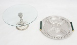 Lote constando de duas peças, sendo porta petiscos com bandeja Italiana em inox com borda vazada e alças laterais em metal com pátina verde e dourada, parte interna com quatro recipientes para petiscos em demi cristal med. 4x32x32 cm de diâmetro e um prato para bolo com bandeja redonda em demi cristal bisotado, coluna e base em metal espessurado a prata, base com placas de madrepérola med. 16x31 cm de diâmetro.