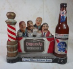 BEBIDAS / COLECIONISMO - ANTIGO DISPLAY DE LOJA - PROPAGANDA EM ALUMÍNIO DA CERVEJA PABST BLUE RIBBON BEER - REPRESENTADA POR UM BALCÃO DE BARBEARIA COM QUATRO CANTORES - ACOMPANHA UMA GARRAFA EM PLÁSTICO PARAFUSADA NA PEÇA - MEDE 30 X 27,5 X 10 CENTÍMETROS.