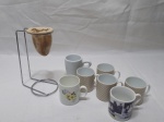 Lote composto de 7 xícaras de café diversas em porcelana e 1 coador de café. Medindo o suporte em metal prateado 16cm de altura.