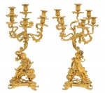 Excepcional Par de Candelabros Bronze dourado a ouro, confeccionado para seis (6) velas em cada peça, no estilo "Louis XV", com um "petit amour" em cada base. França - Século XIX. Med. 70 x 38 x 26 (medidas totais). Marcas do tempo. Pontos com desgastes na douração. Peça de coleção que dispensa comentários. Acervo Particular Rio de Janeiro/RJ. Nota:  Candelabros no estilo Louis XV, feitos em bronze dourado e com o tema" petit amour", é uma peça que remete à opulência e ao romantismo do Rococó francês, característico do reinado de Luís XV (17151774). Esses candelabros seriam típicos de salões nobres ou de coleções sofisticadas, e sua autenticidade pode influenciar diretamente o valor de mercado. Características típicas:1. Estilo Rococó: Linhas sinuosas e formas assimétricas, com ornamentos elaborados, como arabescos e elementos naturais (flores, folhas, conchas).2. Bronze dourado: Peças de alta qualidade geralmente eram douradas com a técnica de douramento por mercúrio, conferindo brilho e durabilidade.3. Tema petit amour: Representações de putti ou querubins (figuras infantis angelicais), frequentemente envolvidas em cenas alegres ou românticas, que eram comuns na decoração da época.4. Função e estética: Os candelabros não apenas iluminavam, mas também serviam como demonstrações de riqueza e bom gosto.